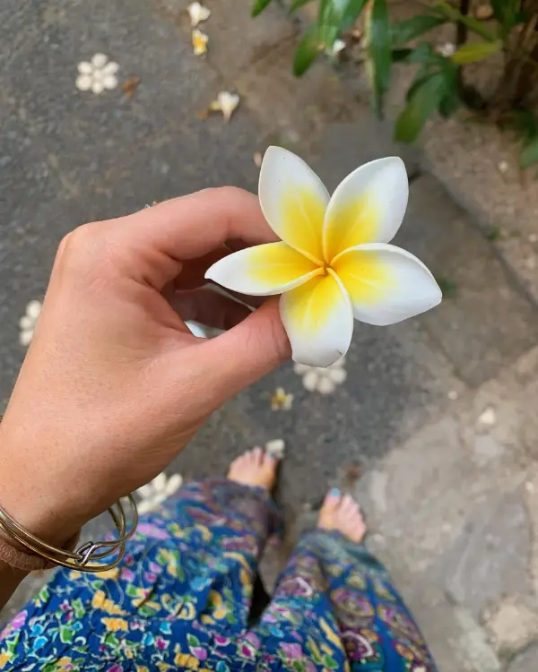 Bali flower, held in the hand of a solo female traveler looking down as they walk