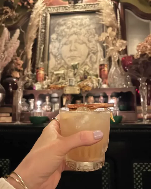 Cocktail in front of prohibition era decor at the Crow and Quill Asheville speakeasy