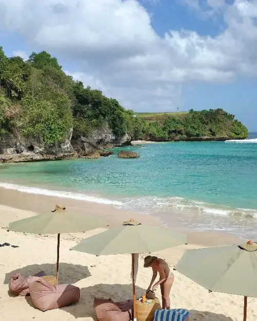 Balangan Beach during a beautiful day with clear azul blue waters and beach umbrellas