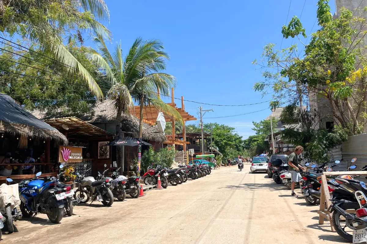 Sun shining in La Punta, where there are bikes lining the side of the road and palm trees overhead, showing that you should consider this area when deciding where to stay in Puerto Escondido