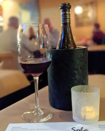 Wine glass and bottle in a dimly lit Sola Bistro & Wine Bar