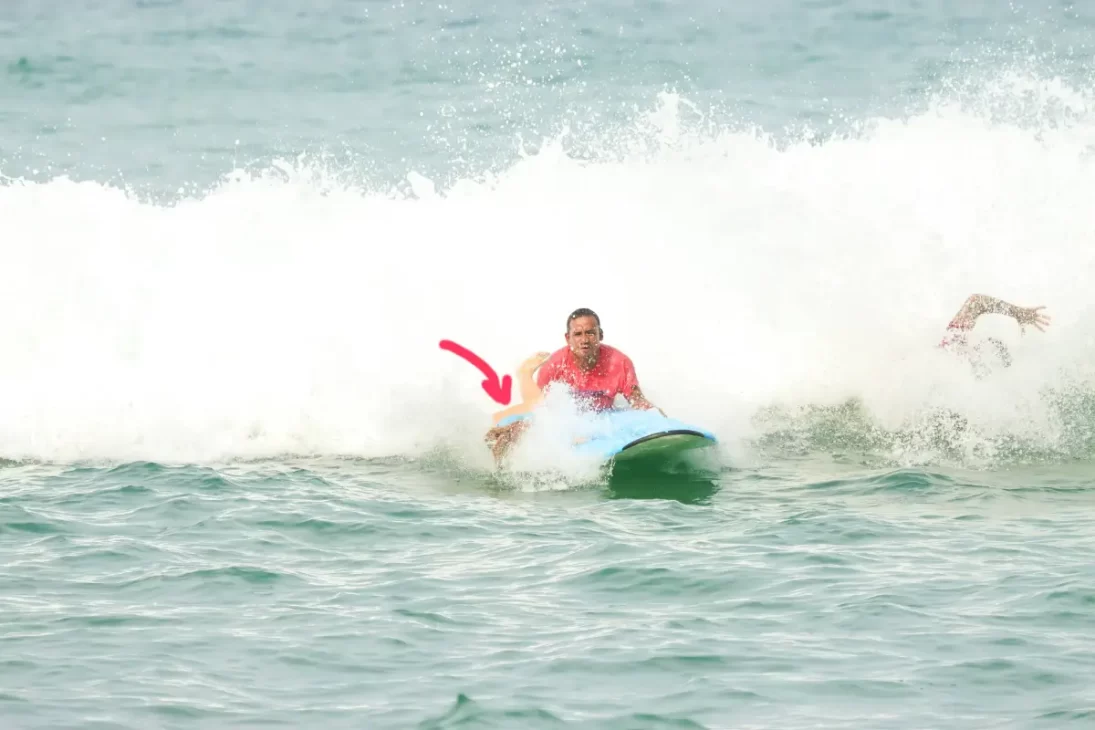 A woman falling off a surf board while the instructor tries to help her and another man is falling off his surf board at the same time, haha to show that not every wave will be great