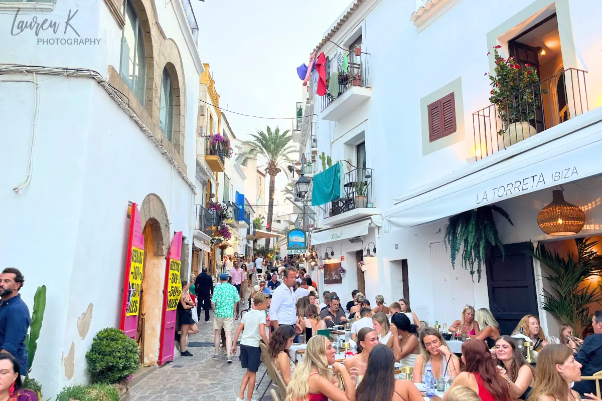 One of the beautiful streets in Ibiza Town, with white buildings, cobblestone streets and people enjoying themselves