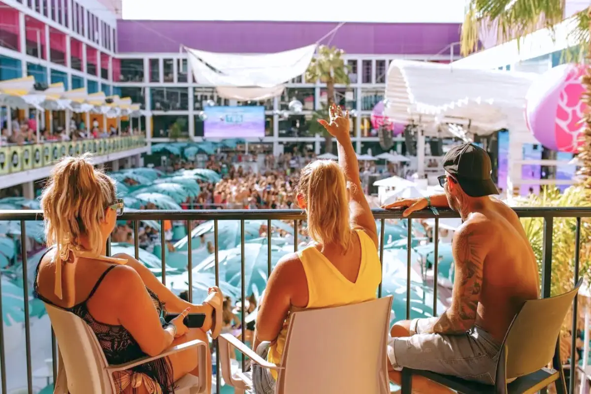 Three people enjoying the show at Ibiza Rocks from their balcony, showing that it's one of the best spots when deciding where to stay in Ibiza for partying