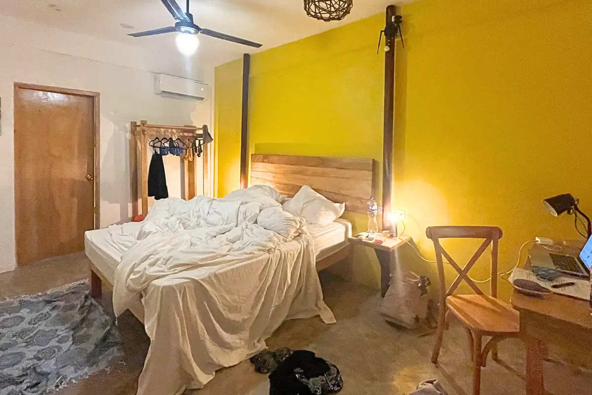 Private room at Selina Puerto Escondido, with a double bed, desk and bright yellow walls