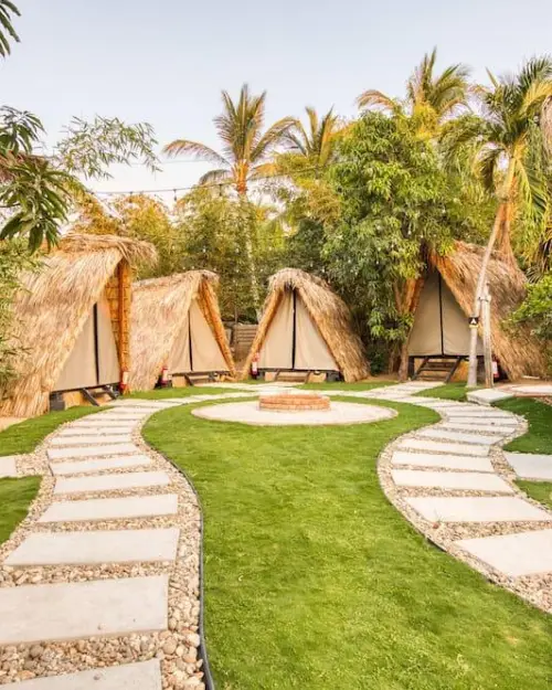 Boho looking teepee tents providing a flaming experience surrounding a mini fire pit in a campground like area 