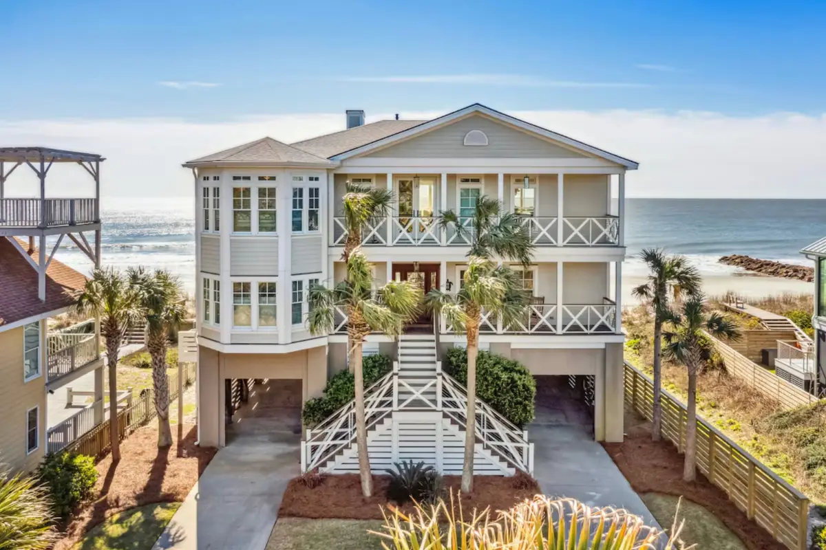 Front view of a stunning oceanfront mansion on a sunny day with the ocean in the background