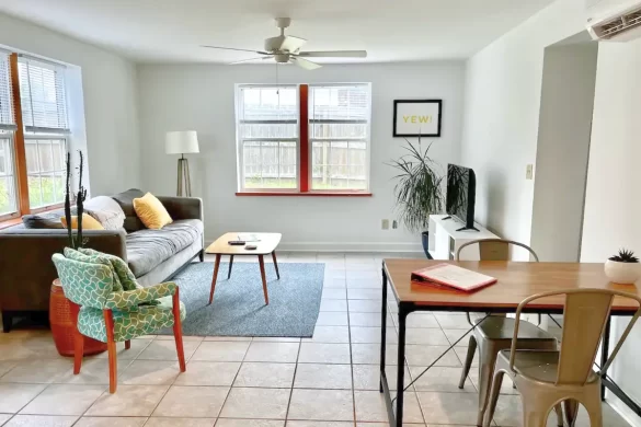 A basic living room with a couch, small TV and table/desk with tile flooring