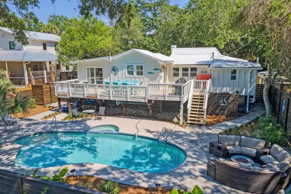 Backyard of a beach house rental in Folly Beach with a partially shaded pool amongst the trees