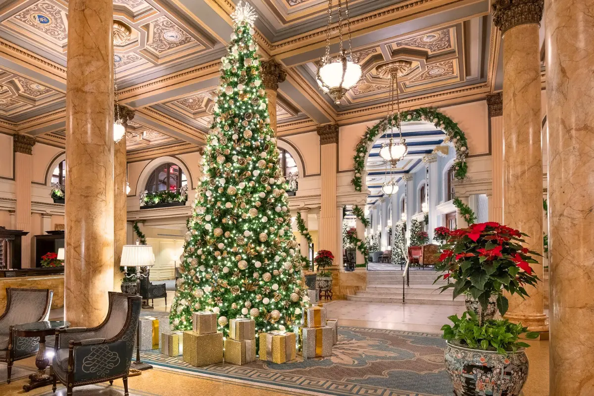 The lobby of the Willard Hotel in DC during the holidays with a giant lit up Christmas tree, garlands and poinsettias under beautiful architecture