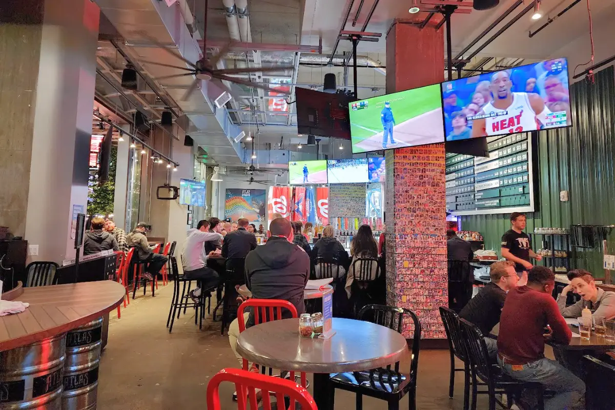 Atlas Brewing Navy Yard's indoor taproom with people sitting at tables and sports on the TVs