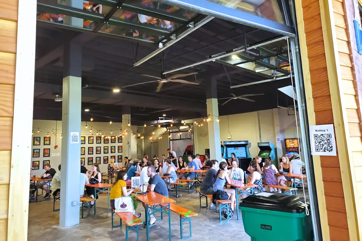 A crowded interior at City-State Brewing Co, where there's an indoor/outdoor feel and arcade games