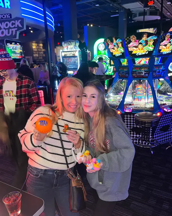 Lauren of Inspired Backpacker and sister holding up their prizes from the claw machine