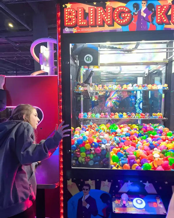 Girl looking at the ducks in a crane machine at Dave and Busters Fairfax to line up her shot