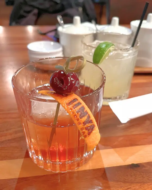 An Old Fashioned drink and Margarita, where the Old Fashioned has a Jinya branded orange on it