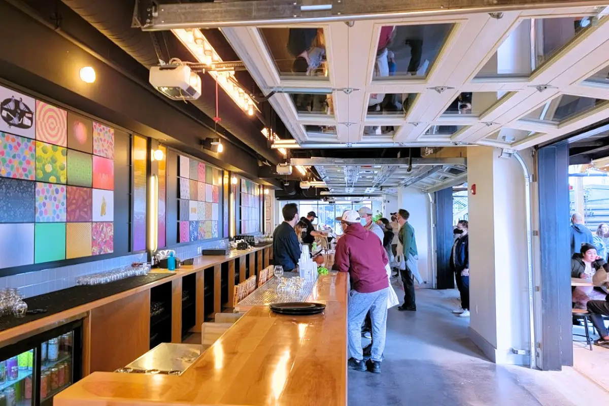 A covered outdoor space at Other Half Brewing with people standing at the bar