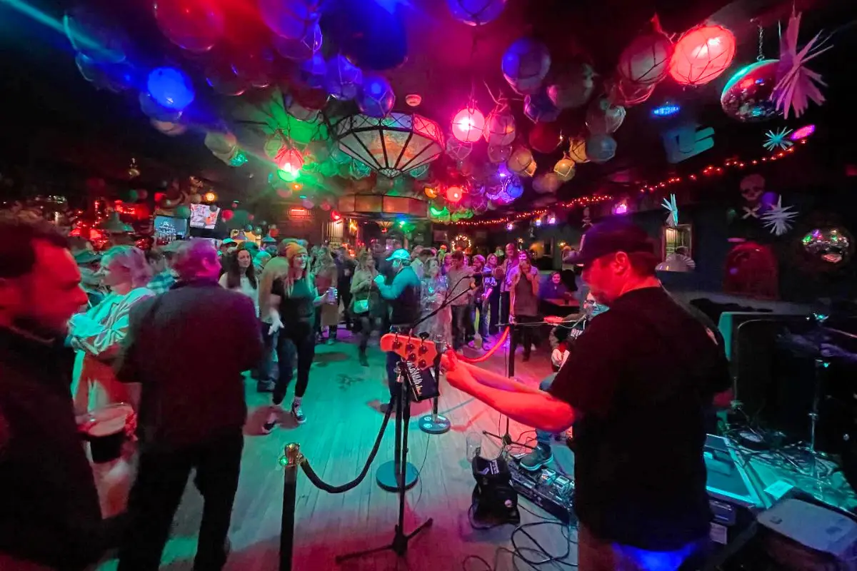 Shot behind the band looking out into the bar at Bounty Bar, with neon glowing lights and lots of people, showing that Bounty Bar is the best spot for lively Folly Beach nightlife