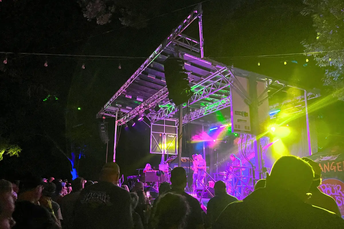 In the Lot stage glowing with neon lights during a night time performance with a big crowd