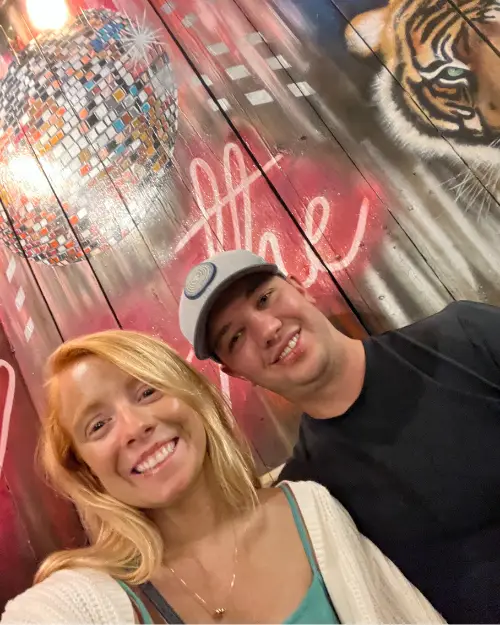 Selfie of Lauren of Inspired Backpacker and husband in front of some artwork at the venue