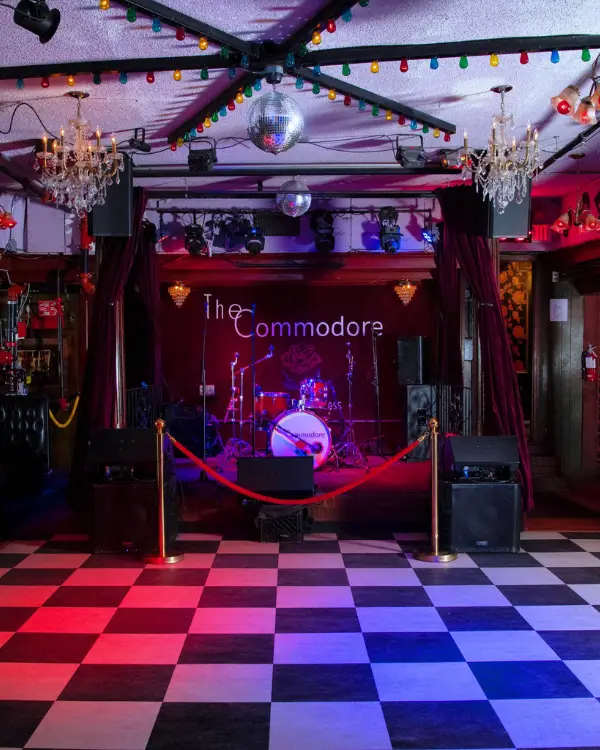 The empty stage at the Commodore with checkered floor below, photographed before the band takes stage and the crowd fills the space, to visualize how the Commodore is a unique spot for live music Charleston SC with charm