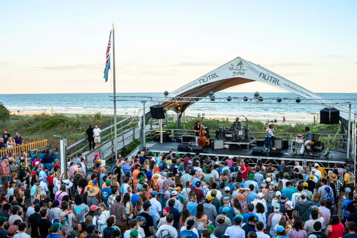 The outdoor stage with the beach in the background during sunset at the Windjammer, with a band playing for a crowd