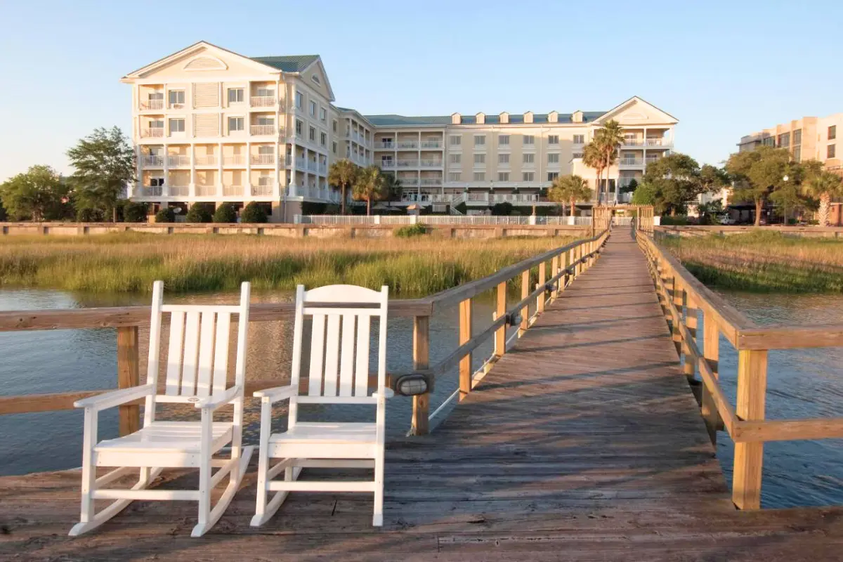 Two chairs at the end of a long dock which connects to the Courtyard Charleston Waterfront, showing that it's a scenic hotel with nice amenities