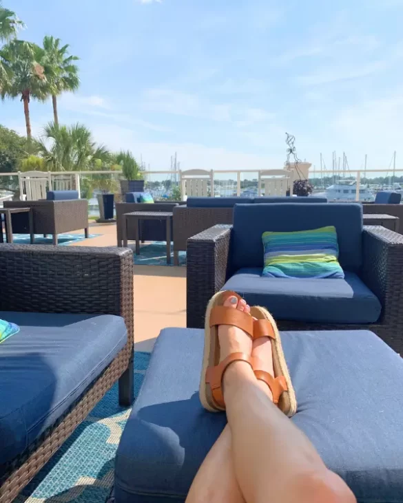 Woman's feet resting on an outdoor lounge chair under a sunny sky