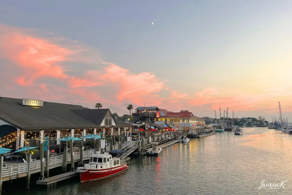 Photograph I took during sunset at Shem Creek under a crescent moon with restaurants and bars along the water